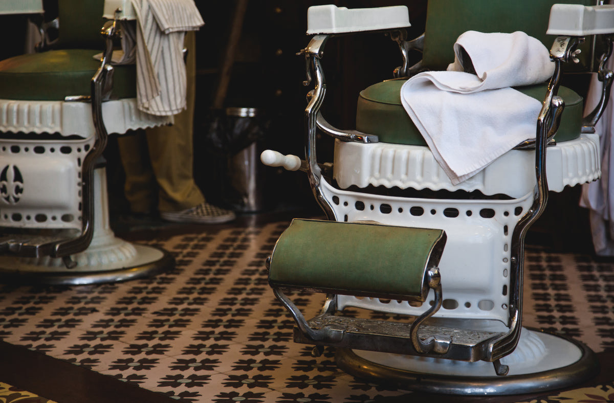 Barbershop interior with barber chairs, mirrors and customers waiting on a bench