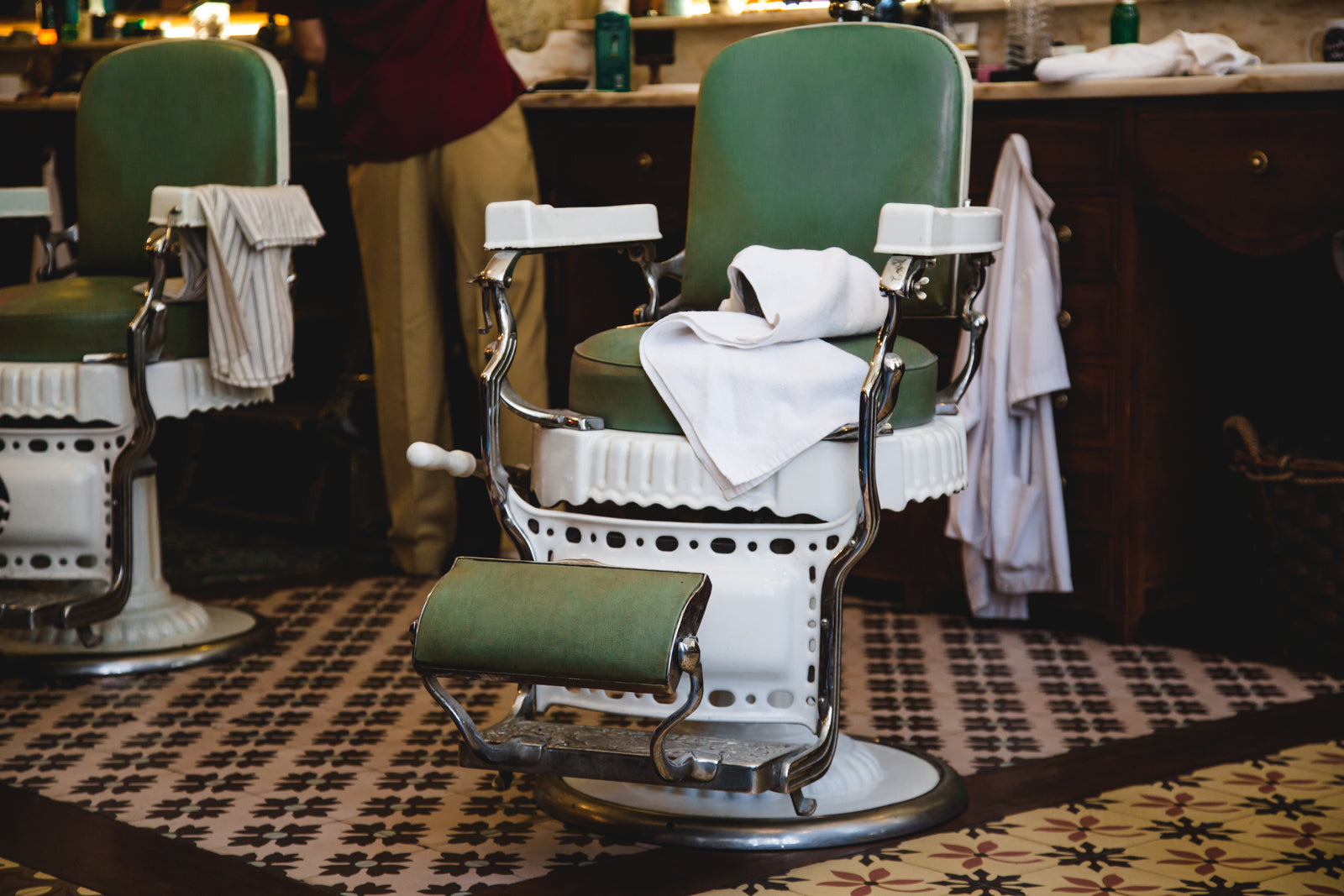 Barbershop interior with barber chairs, mirrors and customers waiting on a bench