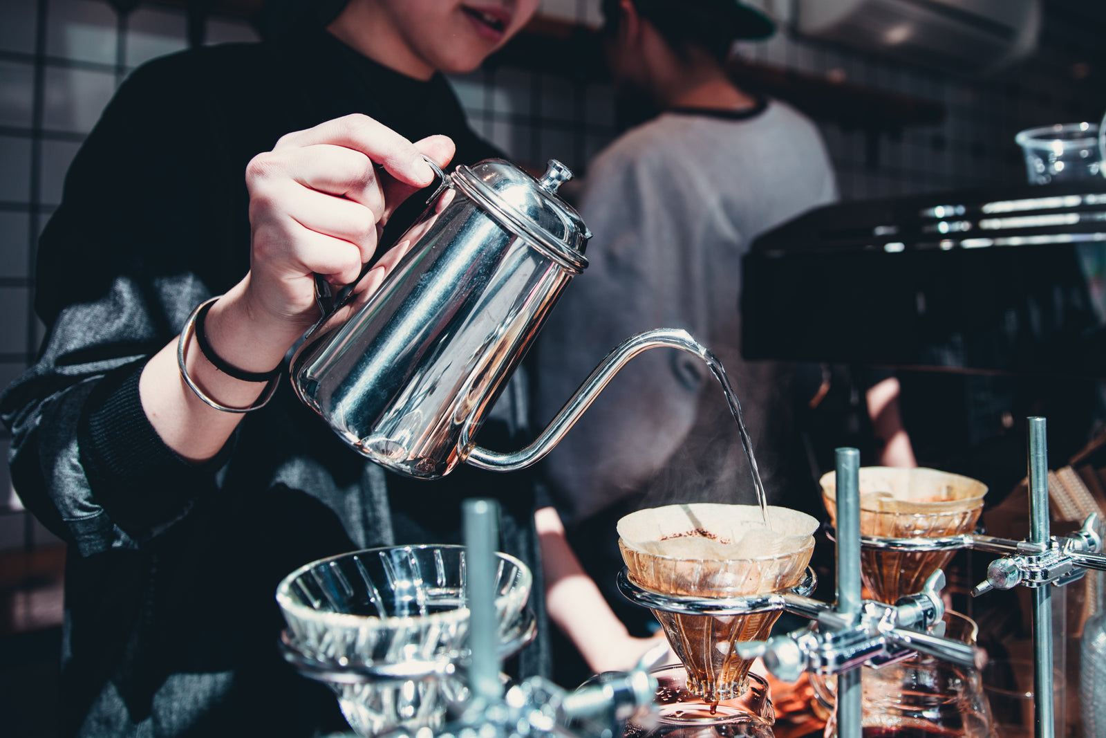 Customers waiting in line at a coffee shop counter while a barista takes orders