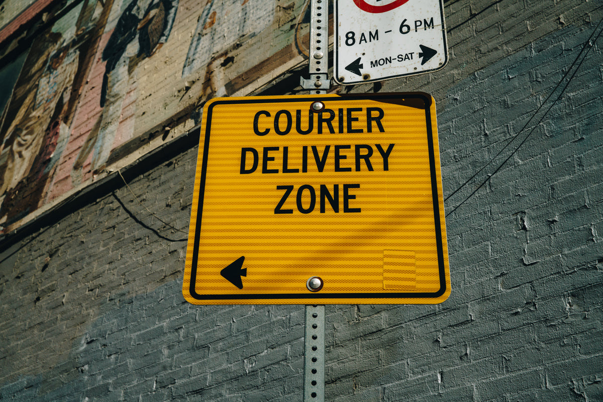 Delivery rider reading a ready-order screen while collecting a packed food order at a kitchen counter