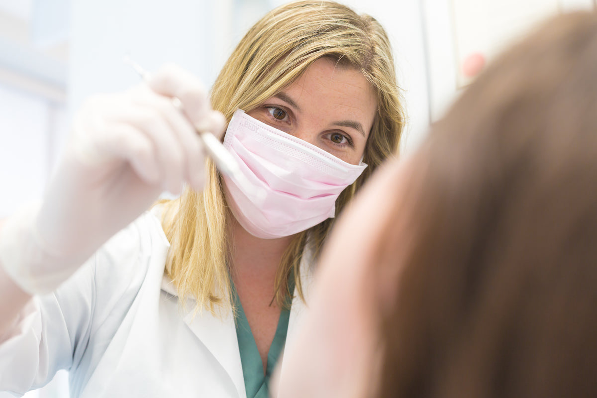 A dentist and assistant working beside a dental chair in an Indian clinic