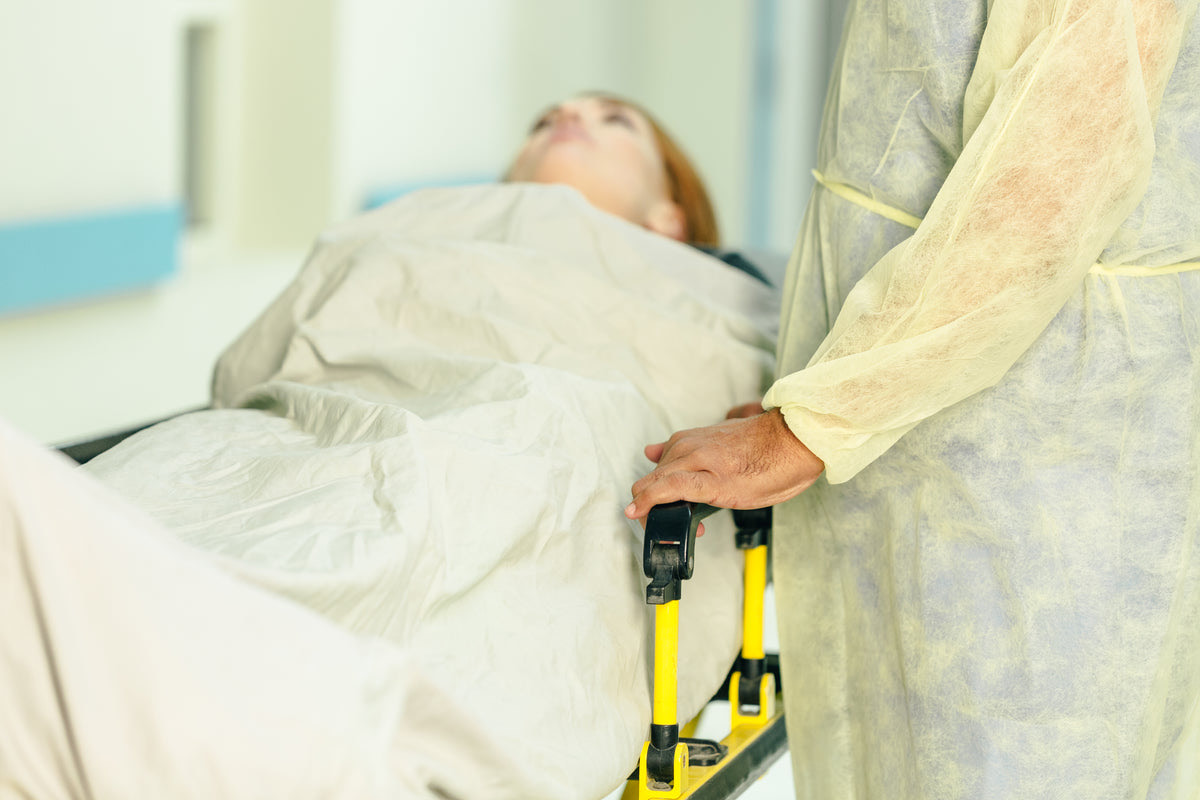 Nurse walking beside a patient bed being moved along a hospital ward corridor