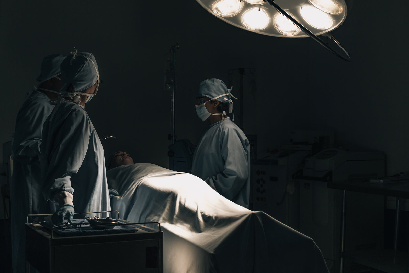 Hospital staff moving an empty patient bed along a corridor between wards