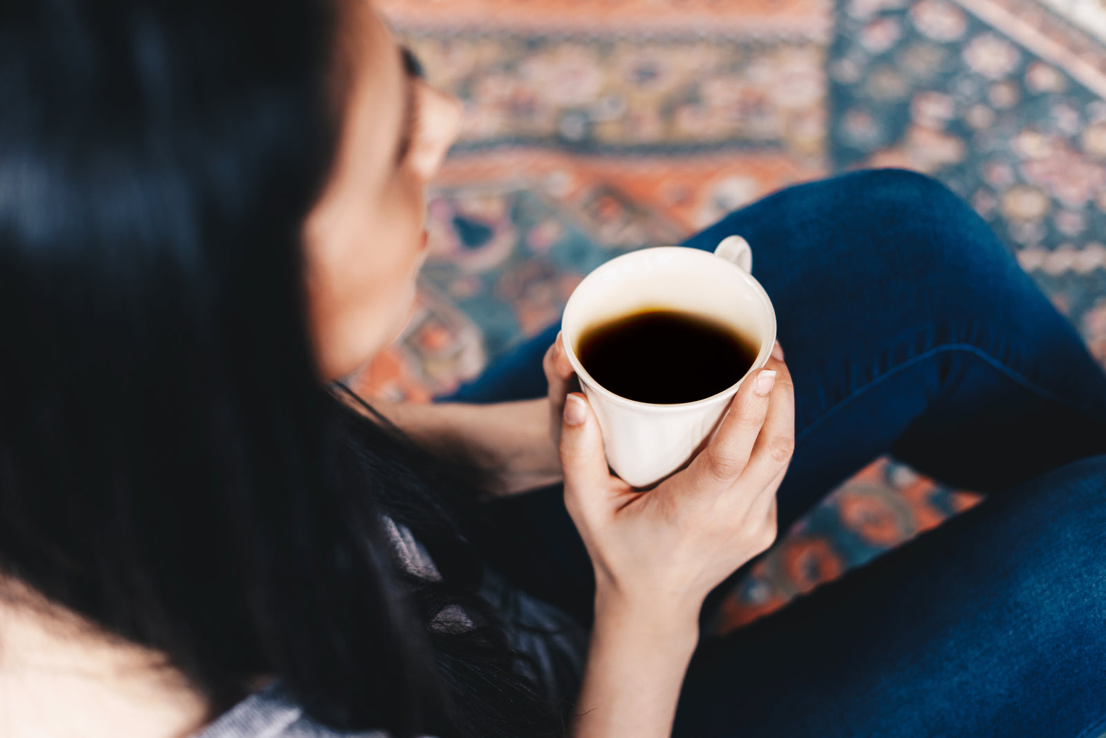 Relaxed woman reading and drinking coffee while waiting in a calm salon lounge