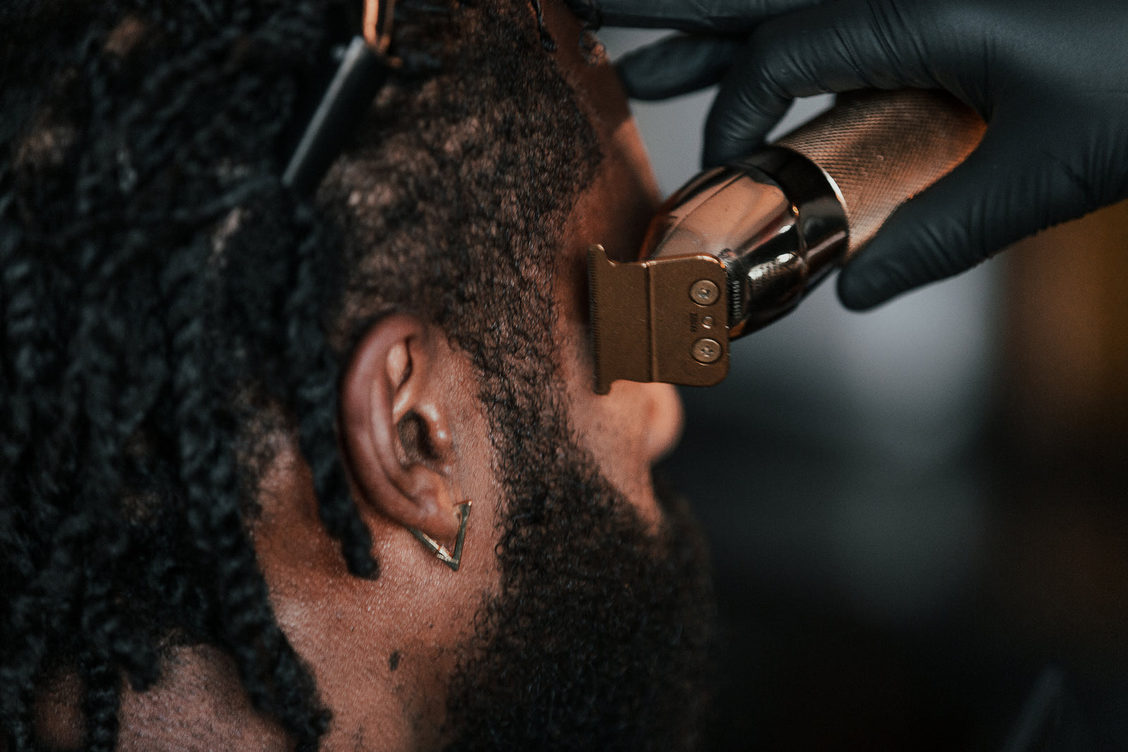 Barber cutting a client's hair while another customer waits for his turn on a bench