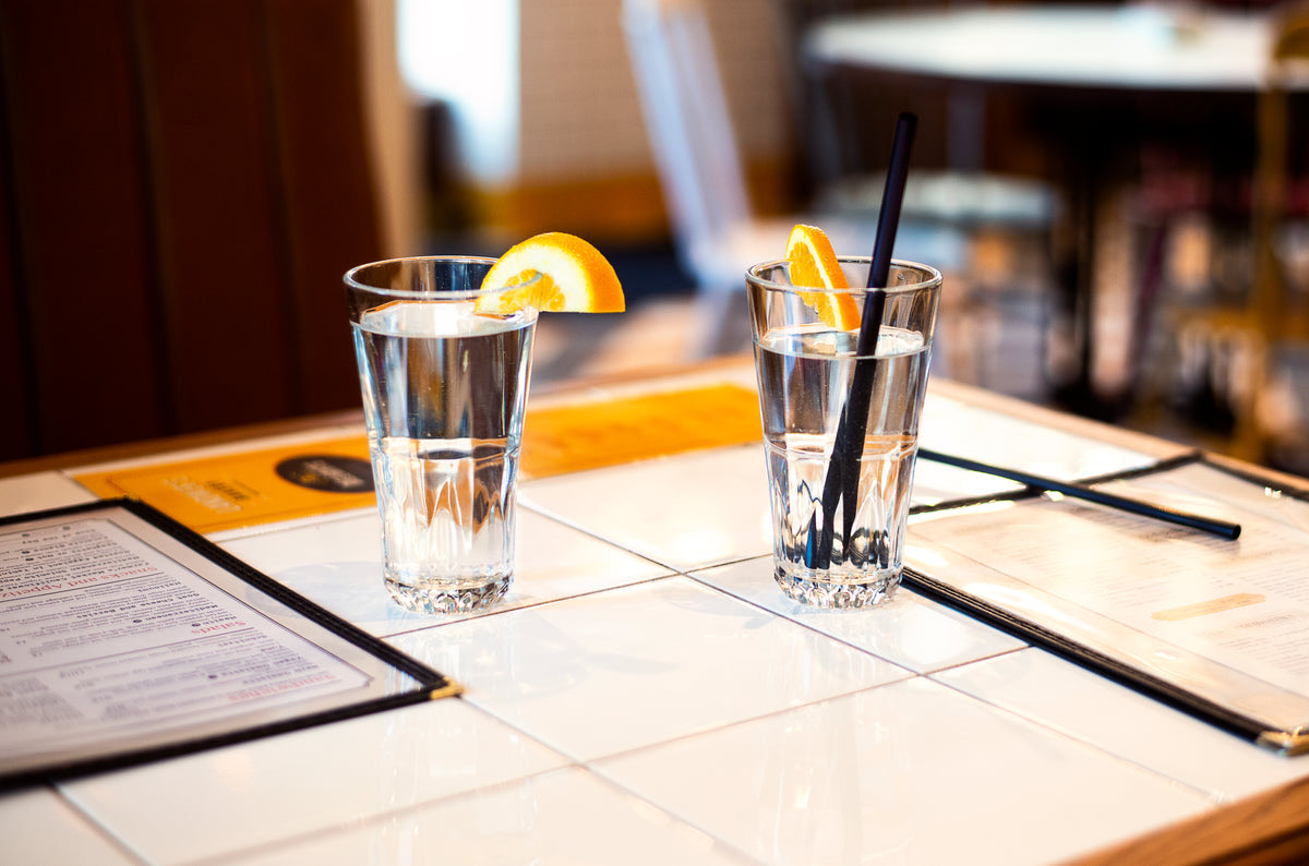 Restaurant table being set with a reservation card while guests wait near the entrance