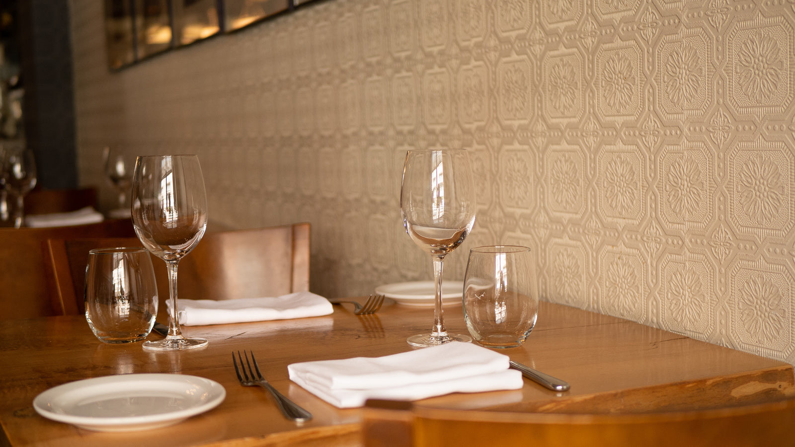 Restaurant table being set with a reservation card while guests wait near the entrance in India