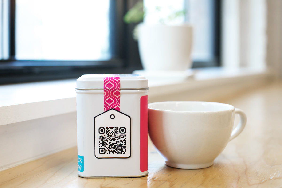 Diner holding a phone over a small QR code stand on a restaurant table while companions look on
