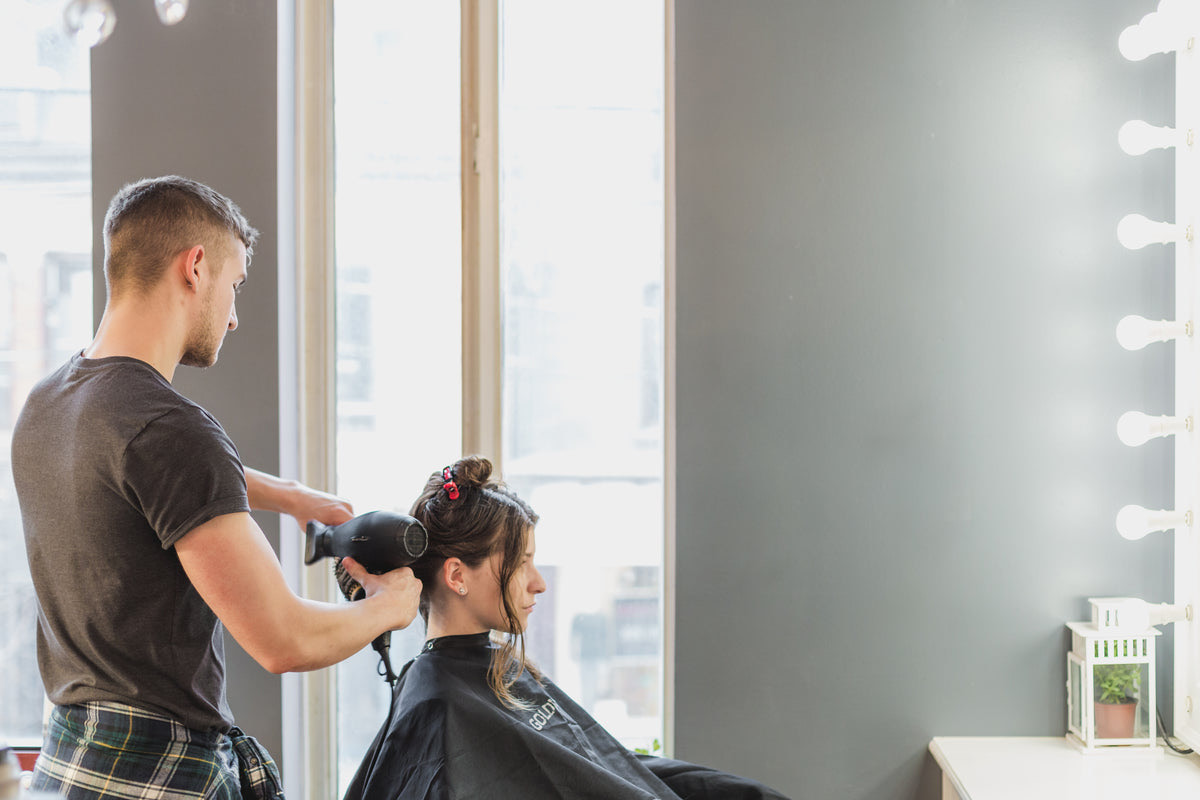 Customers waiting on sofas in a bright modern hair salon with styling chairs behind them