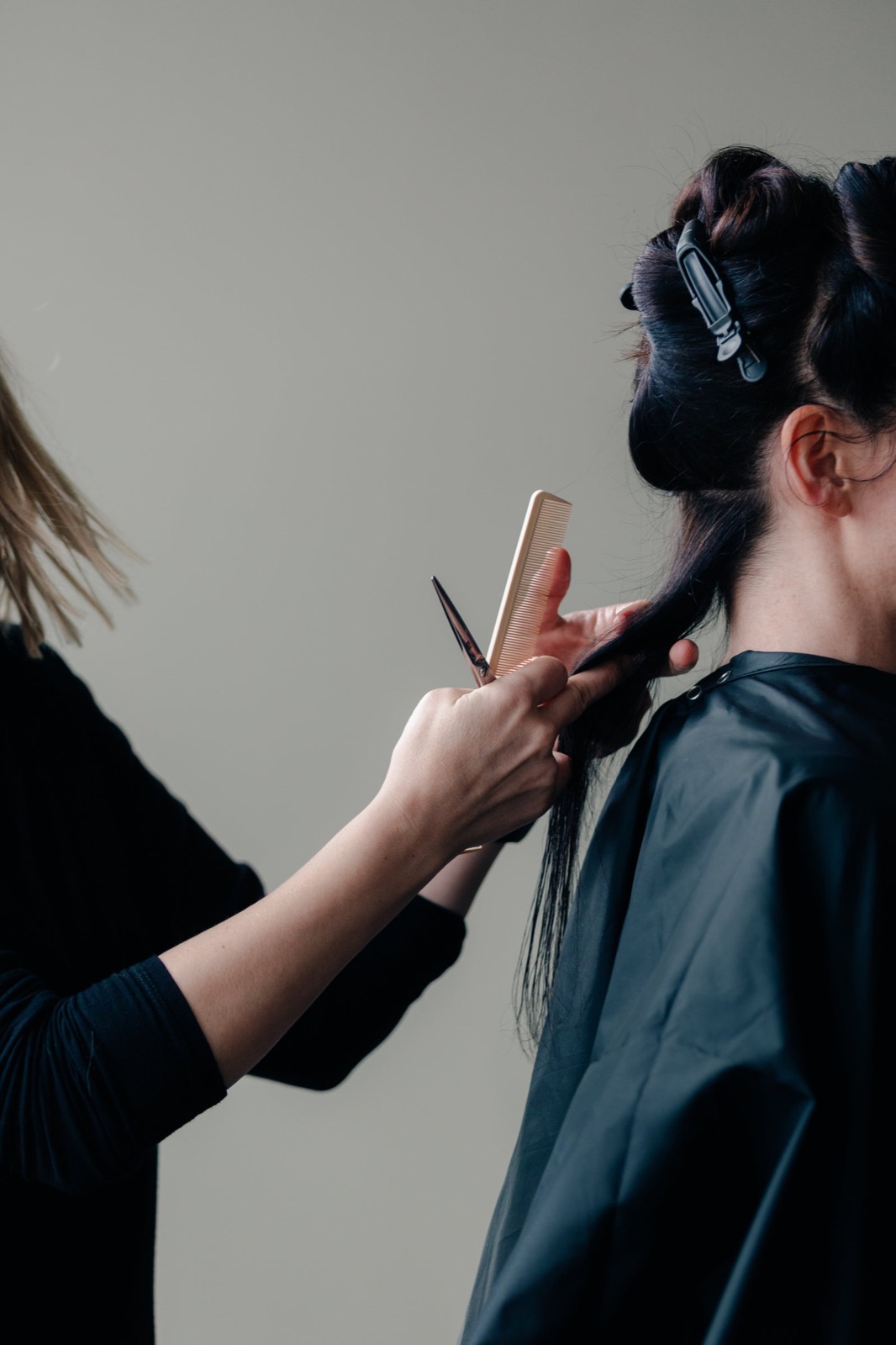 Hair stylist working on a client with another stylist visible in the background of a US salon