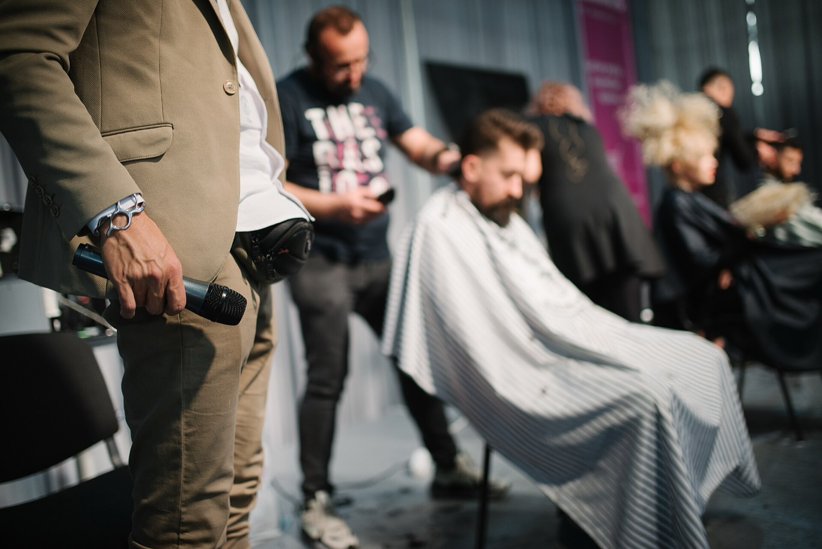 Hair stylist working on a client with another stylist visible in the background of a US salon
