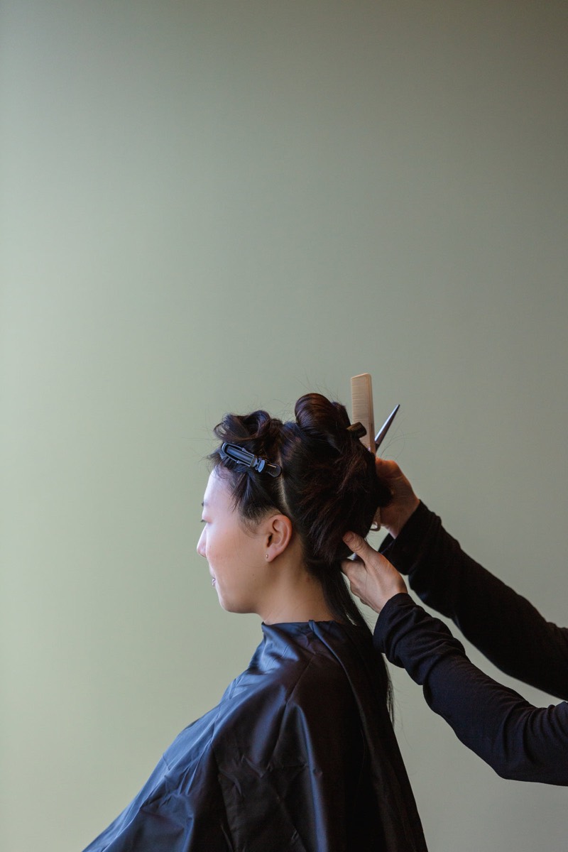 Hairdresser working on a client while waiting customers sit on chairs inside a busy Indian salon