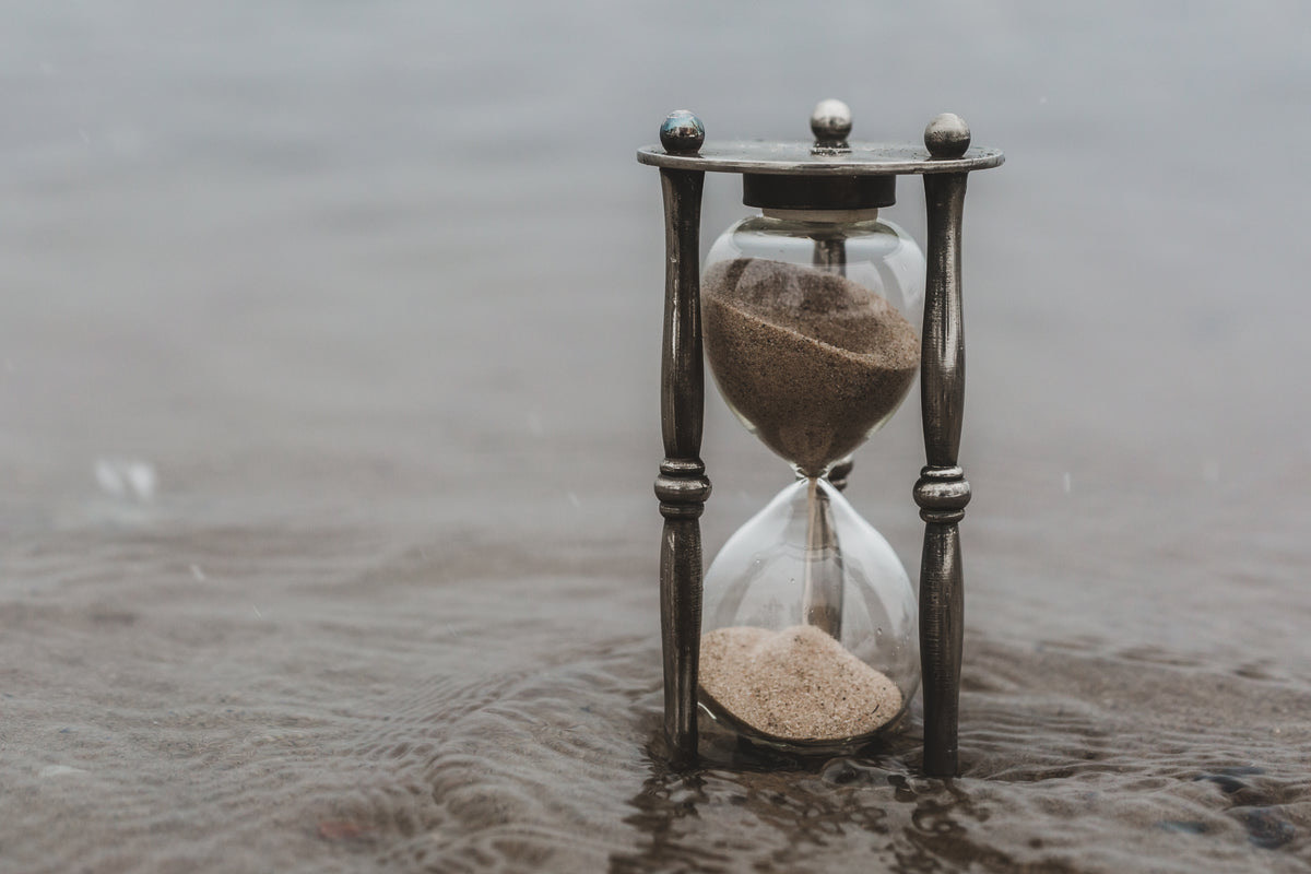 Hourglass with running sand on a spa reception counter beside folded towels