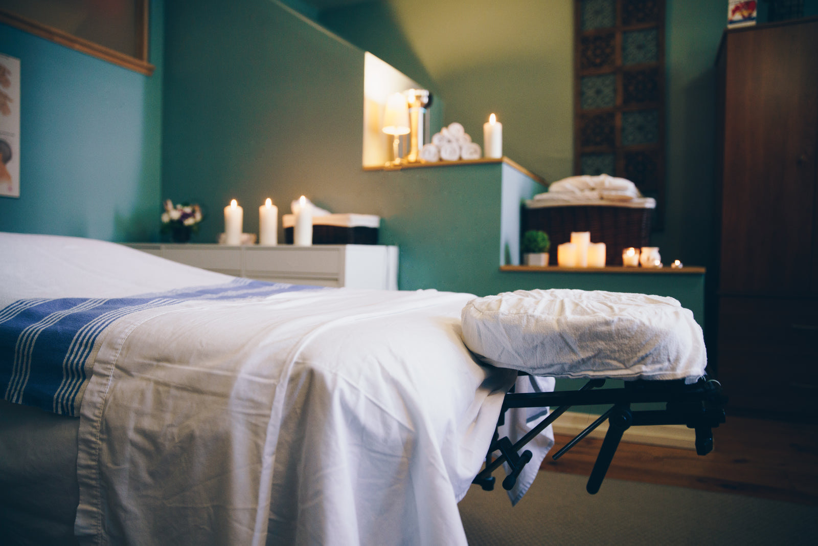 A prepared spa massage room with candles and fresh linens