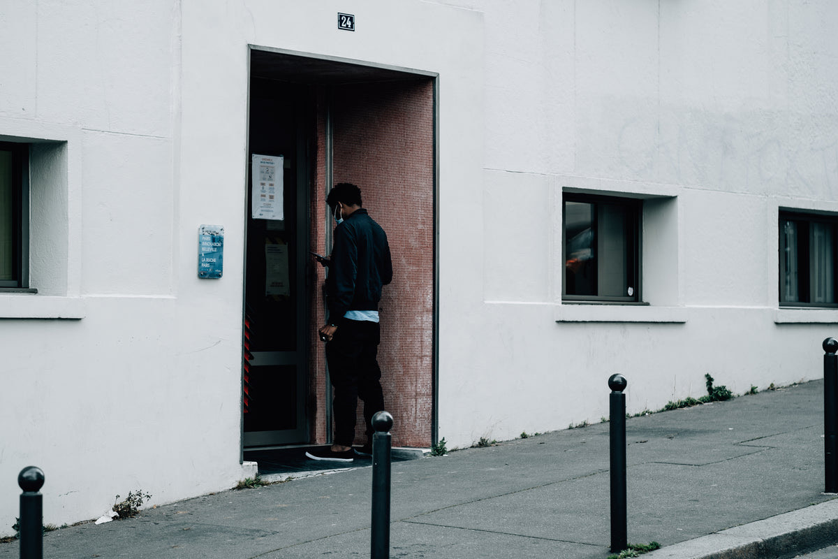 Customer checking a queue notification on a phone while waiting outside a small business