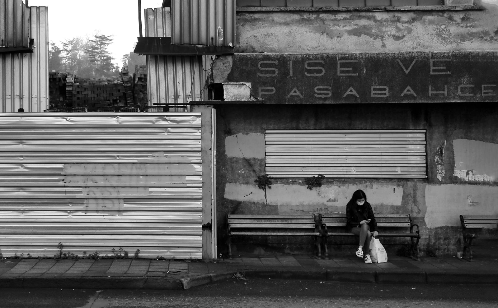 Person checking a queue notification on a phone while waiting outside a small business